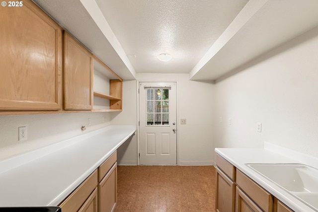 kitchen featuring a textured ceiling, light countertops, and a sink