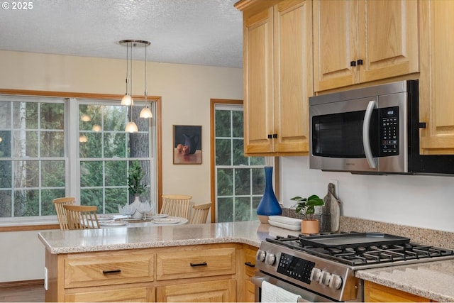 kitchen featuring a peninsula, a textured ceiling, appliances with stainless steel finishes, and a healthy amount of sunlight