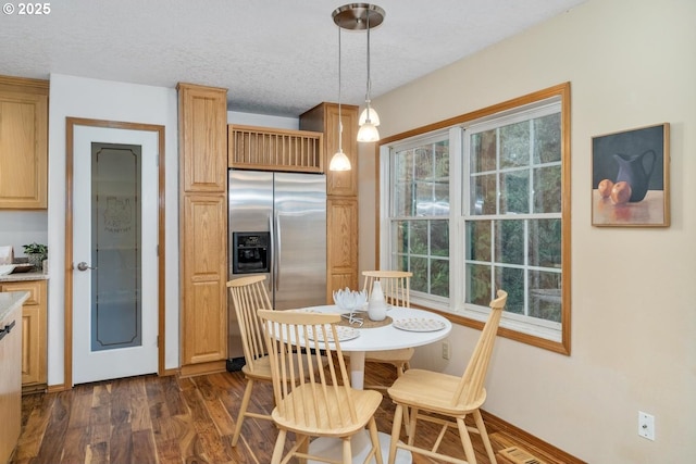 dining room with dark wood-type flooring, a textured ceiling, and baseboards