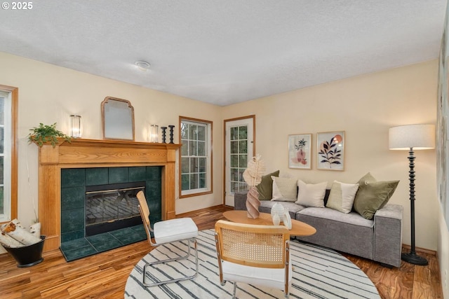 living area featuring baseboards, a tiled fireplace, and wood finished floors