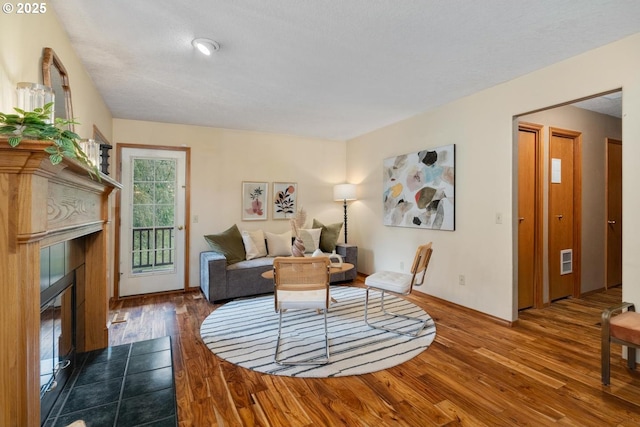 living room with visible vents, a tiled fireplace, and hardwood / wood-style flooring