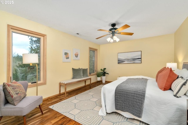 bedroom with baseboards, a ceiling fan, wood finished floors, and visible vents