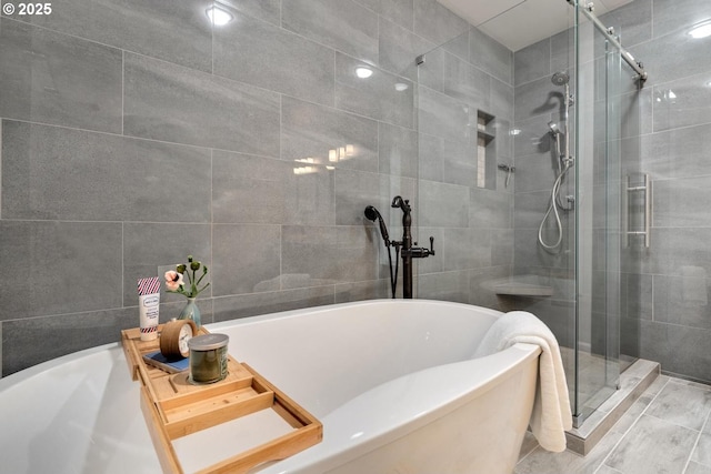 bathroom with a freestanding bath, tile walls, and a stall shower
