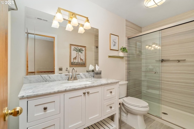 full bathroom with vanity, a shower stall, toilet, and visible vents