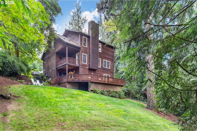 rear view of property with a lawn, a wooden deck, a balcony, and a chimney