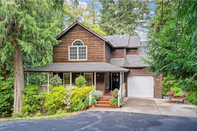 view of front of house with roof with shingles, covered porch, an attached garage, and aphalt driveway
