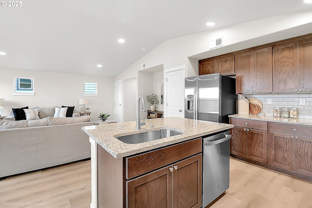 1021 Sommerville Loop, Harrisburg, OR 97446 - kitchen featuring stainless steel appliances, light wood-style floors, a sink, vaulted ceiling, and a kitchen island with sink