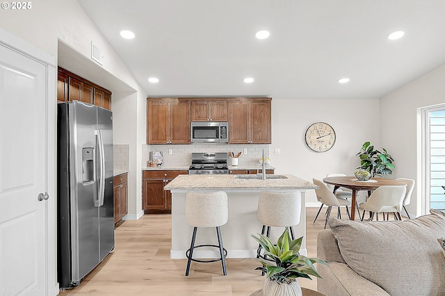 1021 Sommerville Loop, Harrisburg, OR 97446 - kitchen featuring stainless steel appliances, a sink, tasteful backsplash, light wood finished floors, and an island with sink