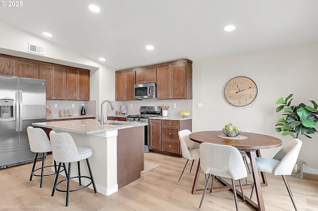 1021 Sommerville Loop, Harrisburg, OR 97446 - kitchen featuring stainless steel appliances, a sink, tasteful backsplash, light wood-style flooring, and vaulted ceiling