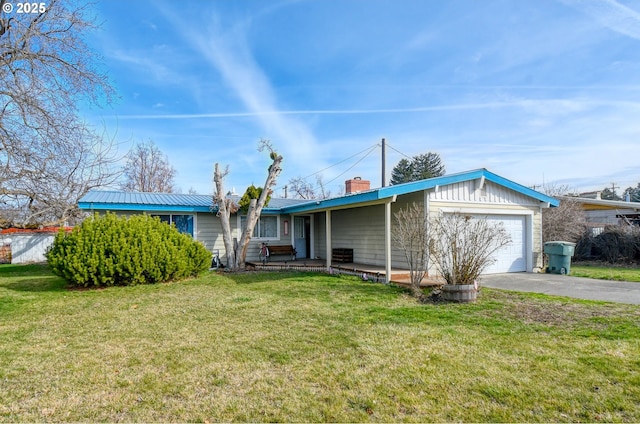 view of front of home with aphalt driveway, a front yard, a chimney, metal roof, and a garage