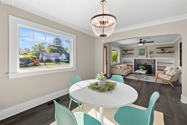 6959 N Denver Ave, Portland, OR 97217 - dining space featuring arched walkways, dark wood-style flooring, baseboards, a fireplace, and crown molding
