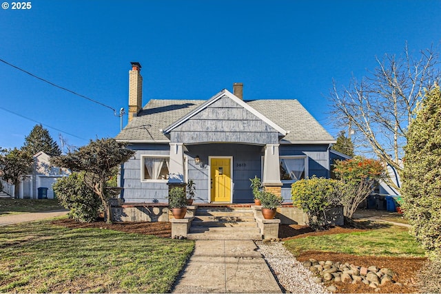 view of front of home with roof with shingles, a chimney, and a front yard