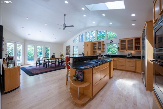 kitchen with open shelves, light wood finished floors, a skylight, recessed lighting, and stainless steel appliances