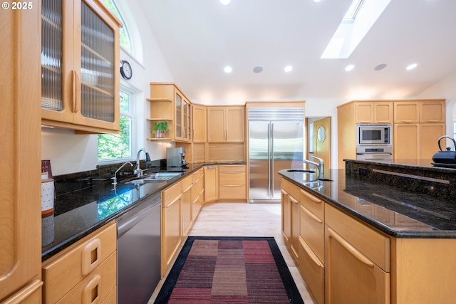 kitchen featuring built in appliances, light brown cabinets, a sink, a skylight, and recessed lighting