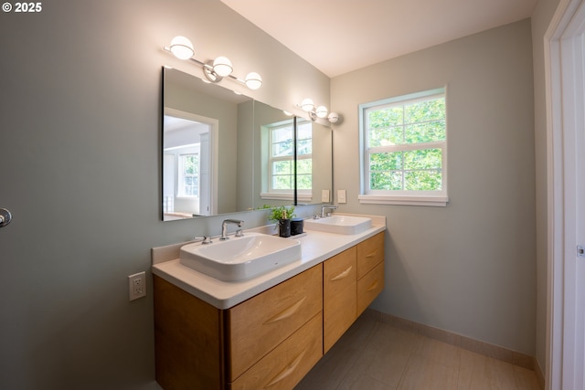 bathroom with double vanity and baseboards