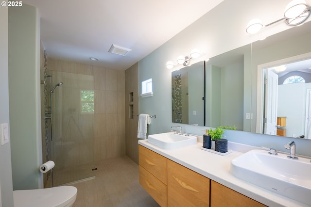 full bath with a tile shower, toilet, double vanity, and tile patterned flooring