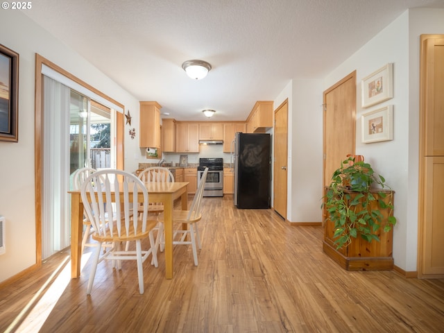 kitchen with light hardwood / wood-style flooring, stainless steel appliances, a textured ceiling, and light brown cabinets