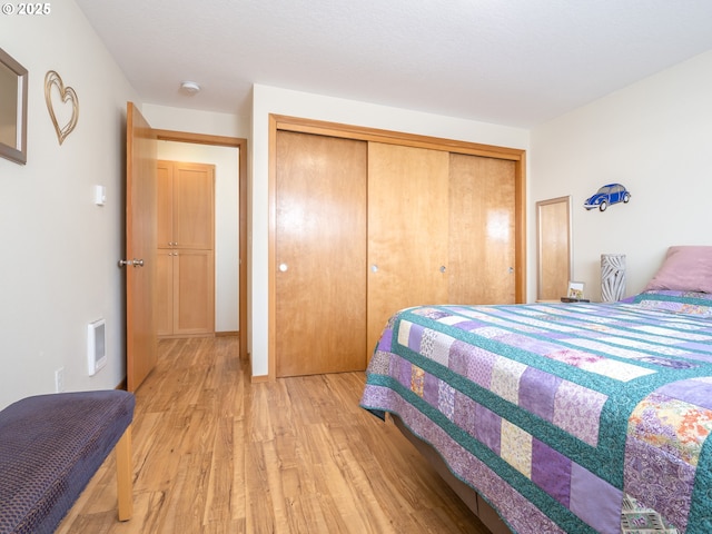 bedroom with light hardwood / wood-style floors and a closet