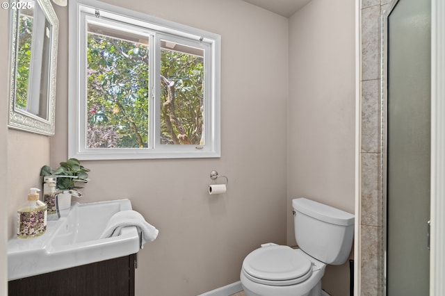bathroom featuring toilet, baseboards, a shower with door, and vanity