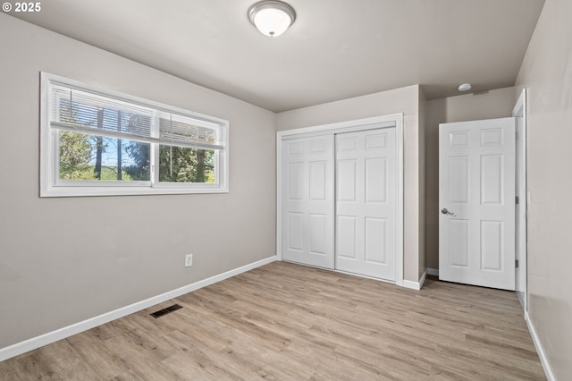 unfurnished bedroom with baseboards, light wood-style flooring, and a closet