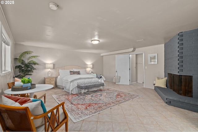 bedroom with a brick fireplace and light tile patterned floors