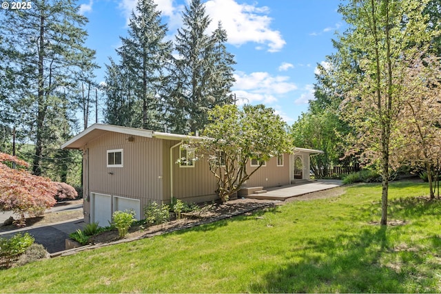 rear view of property featuring a garage, a lawn, and driveway
