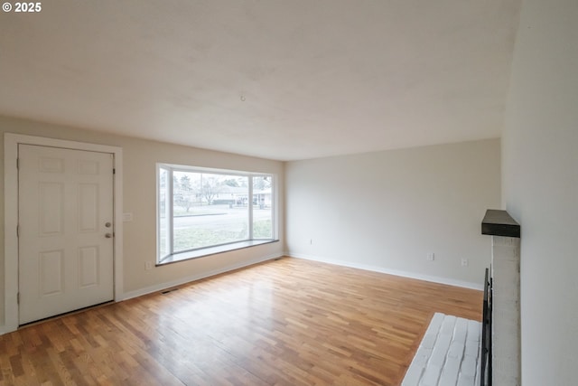 unfurnished living room featuring light wood-style flooring, visible vents, and baseboards