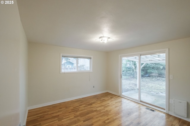 unfurnished room featuring wood finished floors, visible vents, and baseboards