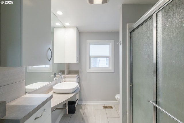 full bath with visible vents, toilet, a shower with shower door, vanity, and baseboards