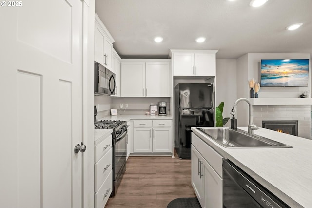 kitchen with wood finished floors, a sink, recessed lighting, and black appliances