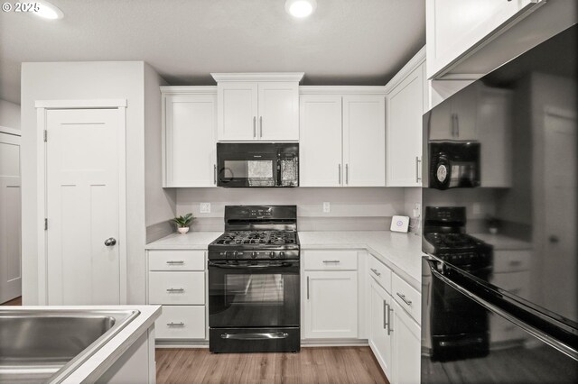 kitchen with recessed lighting, light countertops, black appliances, light wood-style flooring, and white cabinetry