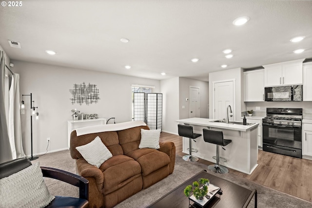 living area featuring visible vents, light wood-style flooring, baseboards, and recessed lighting