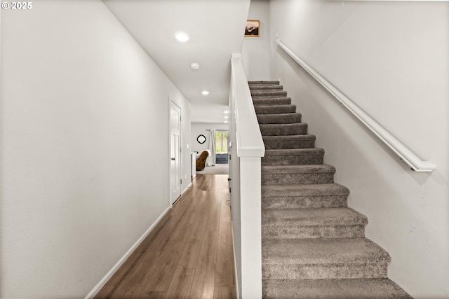 staircase with baseboards, wood finished floors, and recessed lighting