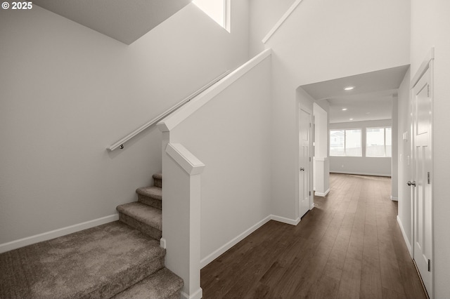 staircase featuring hardwood / wood-style floors and a towering ceiling