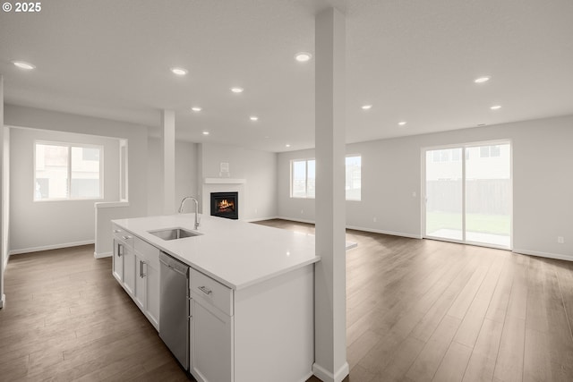 kitchen with sink, dishwasher, a kitchen island with sink, hardwood / wood-style floors, and white cabinets