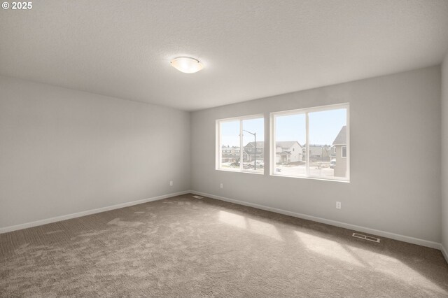 carpeted empty room featuring a textured ceiling