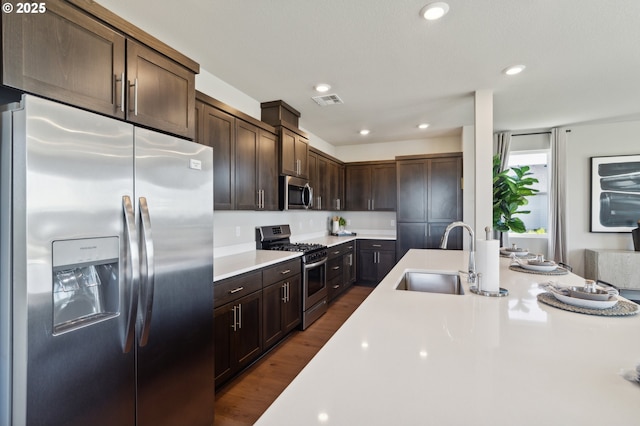 kitchen featuring dark wood-type flooring, dark brown cabinetry, stainless steel appliances, and sink