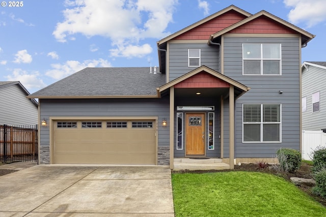 craftsman-style home featuring concrete driveway, roof with shingles, an attached garage, fence, and a front lawn