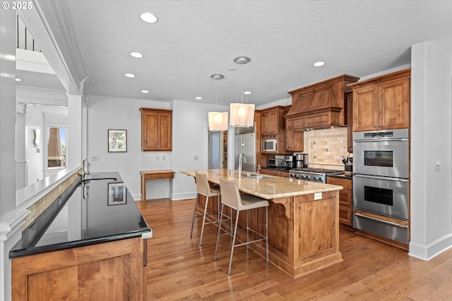 100 Garibaldi St, Lake Oswego, OR 97035 - kitchen featuring built in appliances, a warming drawer, a large island with sink, premium range hood, and light wood-type flooring