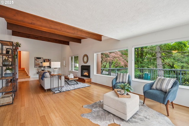 630 SW Viewmont Dr, Portland, OR 97225 - living area with beamed ceiling, a textured ceiling, light wood-type flooring, a glass covered fireplace, and stairs