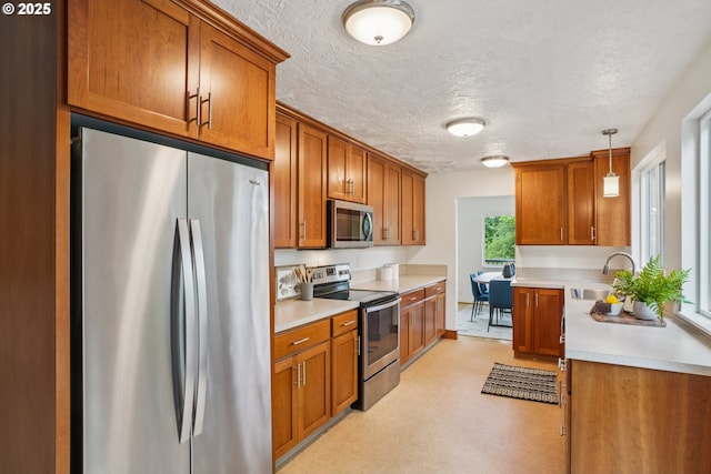 630 SW Viewmont Dr, Portland, OR 97225 - kitchen featuring stainless steel appliances, a sink, brown cabinets, a textured ceiling, and light countertops