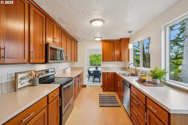 630 SW Viewmont Dr, Portland, OR 97225 - kitchen featuring appliances with stainless steel finishes, a sink, brown cabinetry, light countertops, and a textured ceiling