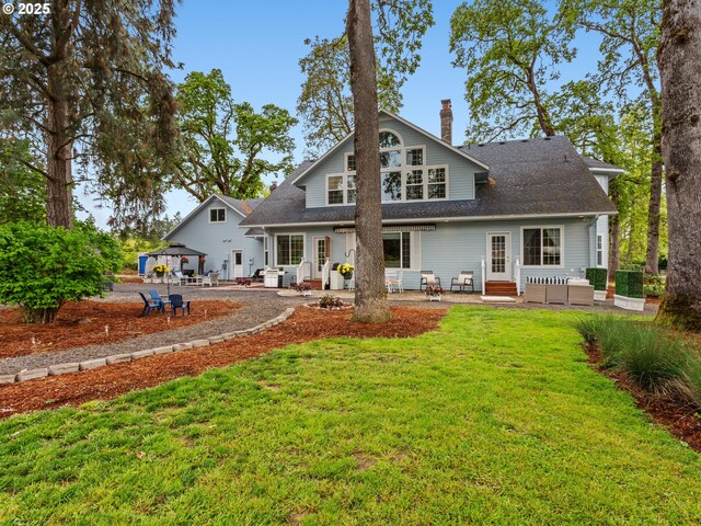 back of house featuring a gazebo, entry steps, a chimney, a patio, and a yard