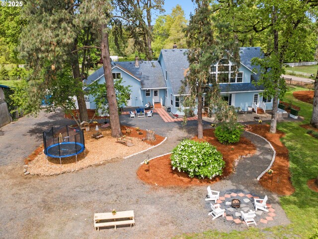 rear view of house with a fire pit, a patio area, and a trampoline