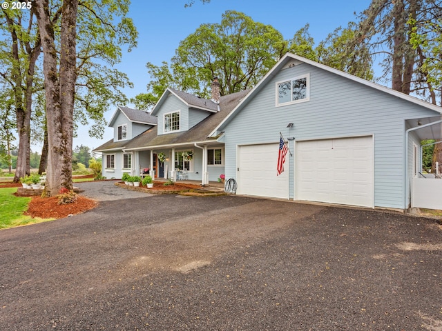 23751 Schultz Rd, Aurora, OR 97002 - view of front of house featuring a porch, asphalt driveway, a chimney, a shingled roof, and a garage