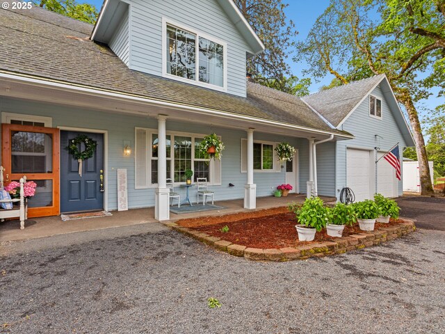traditional-style home featuring a shingled roof, a porch, and driveway