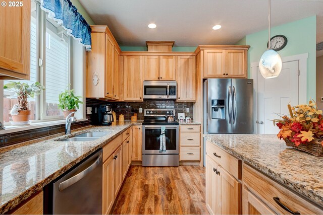 kitchen with light brown cabinetry, decorative backsplash, stainless steel appliances, and a sink