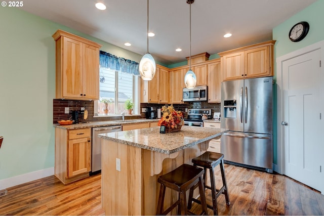 kitchen featuring light wood-type flooring, stainless steel appliances, backsplash, and light brown cabinets