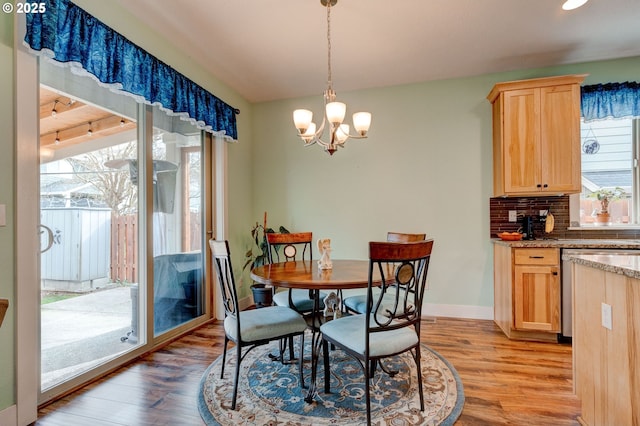 dining space with light wood-style flooring, baseboards, and a chandelier