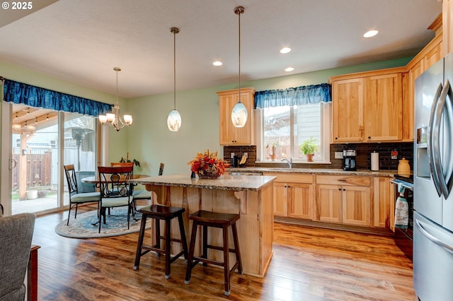 kitchen with a kitchen island, stainless steel fridge, and light brown cabinetry